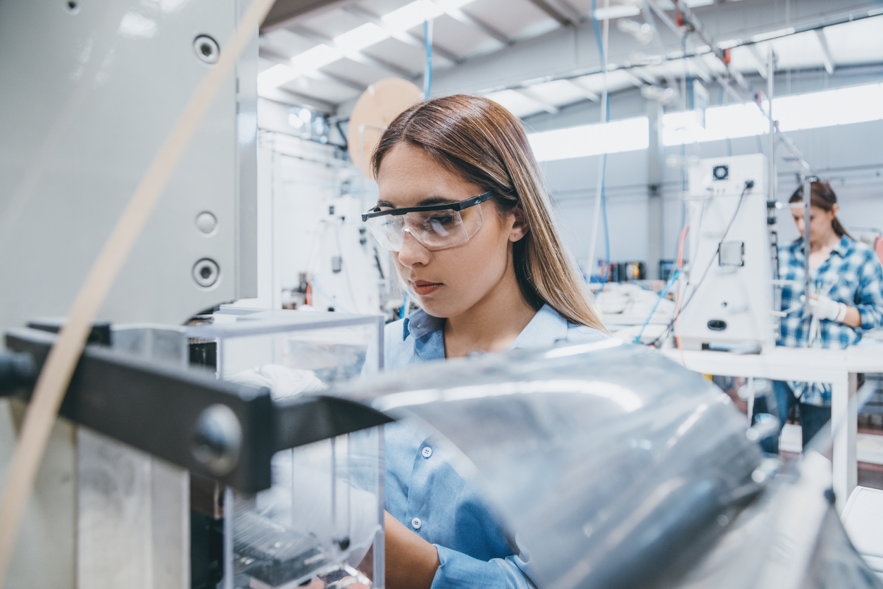 Female industrial worker working with manufacturing equipment in a factory